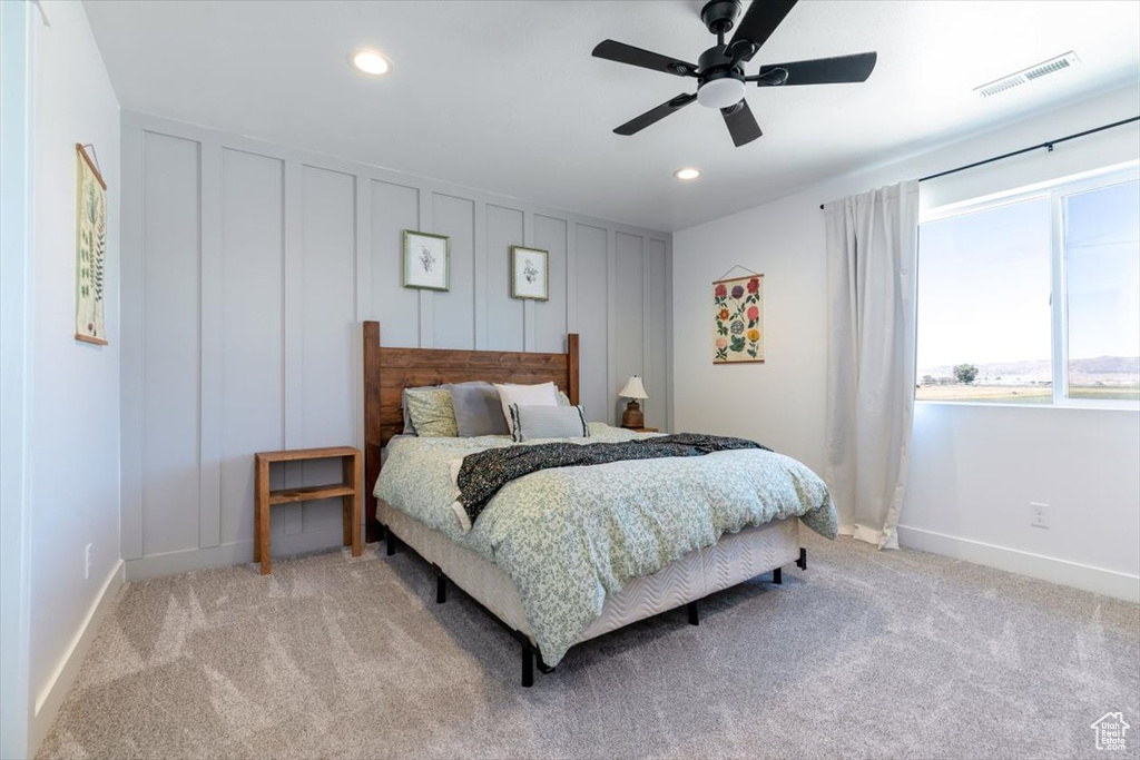 Bedroom featuring light colored carpet, recessed lighting, a ceiling fan, and a decorative wall
