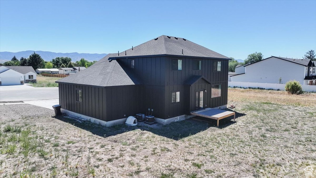 Back of house featuring board and batten siding, roof with shingles, and a mountain view