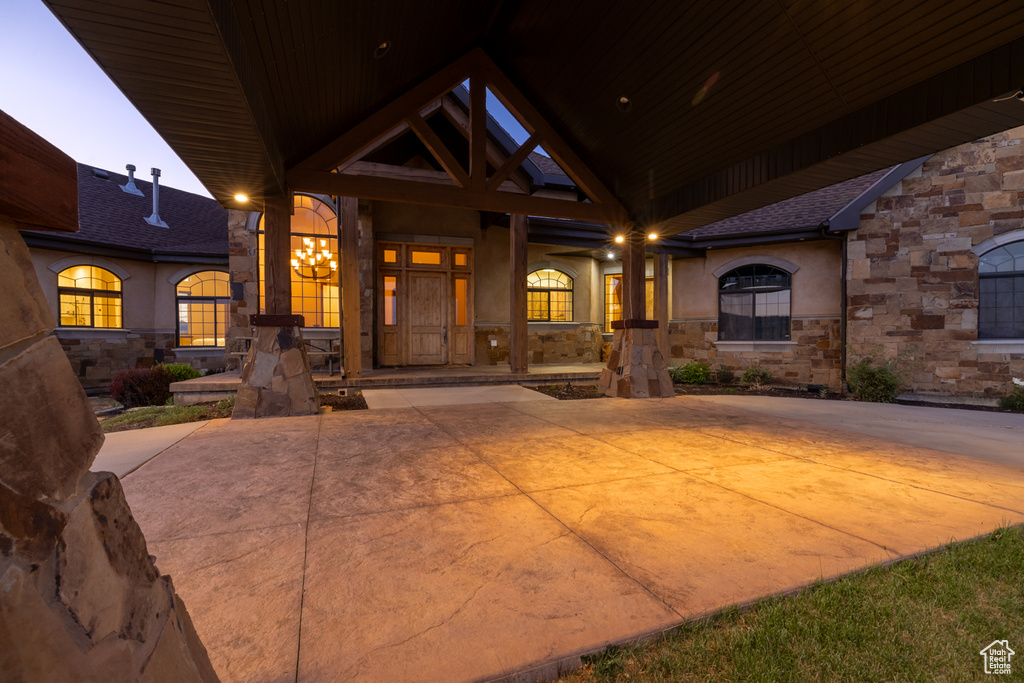 Entrance to property featuring stone siding, stucco siding, and covered porch