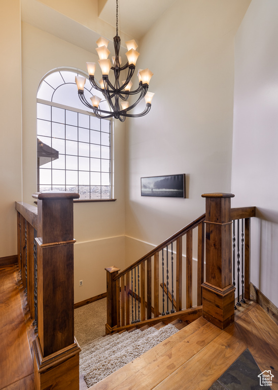 Stairs with hardwood / wood-style floors and a chandelier