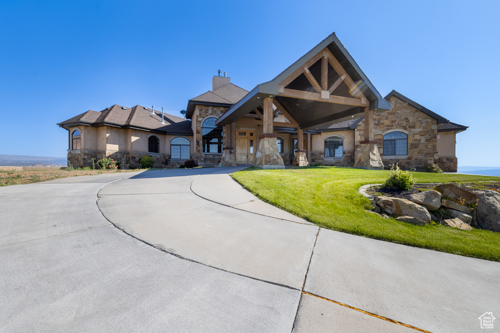 View of front facade featuring stone siding, a chimney, and a front yard