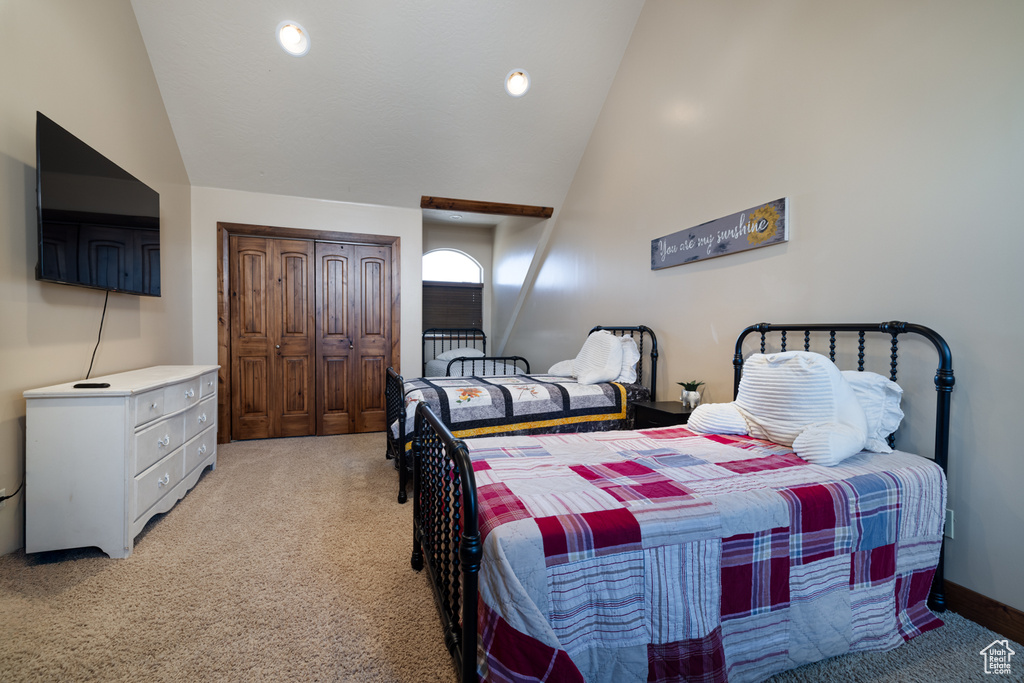 Bedroom featuring light colored carpet, a closet, and high vaulted ceiling