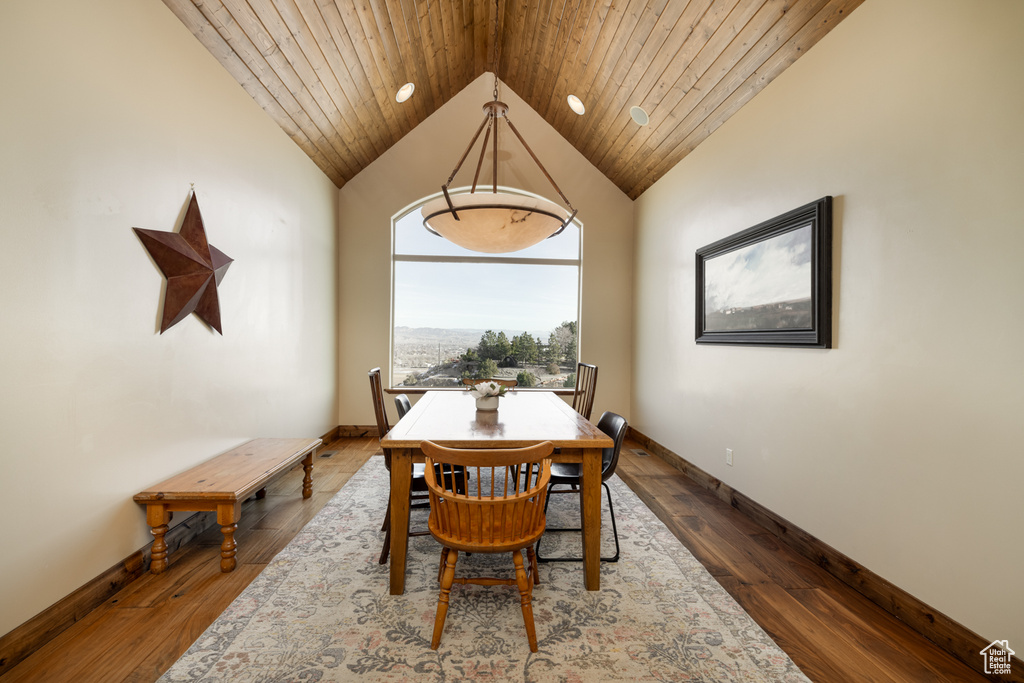 Dining space with dark wood finished floors, vaulted ceiling, and wooden ceiling