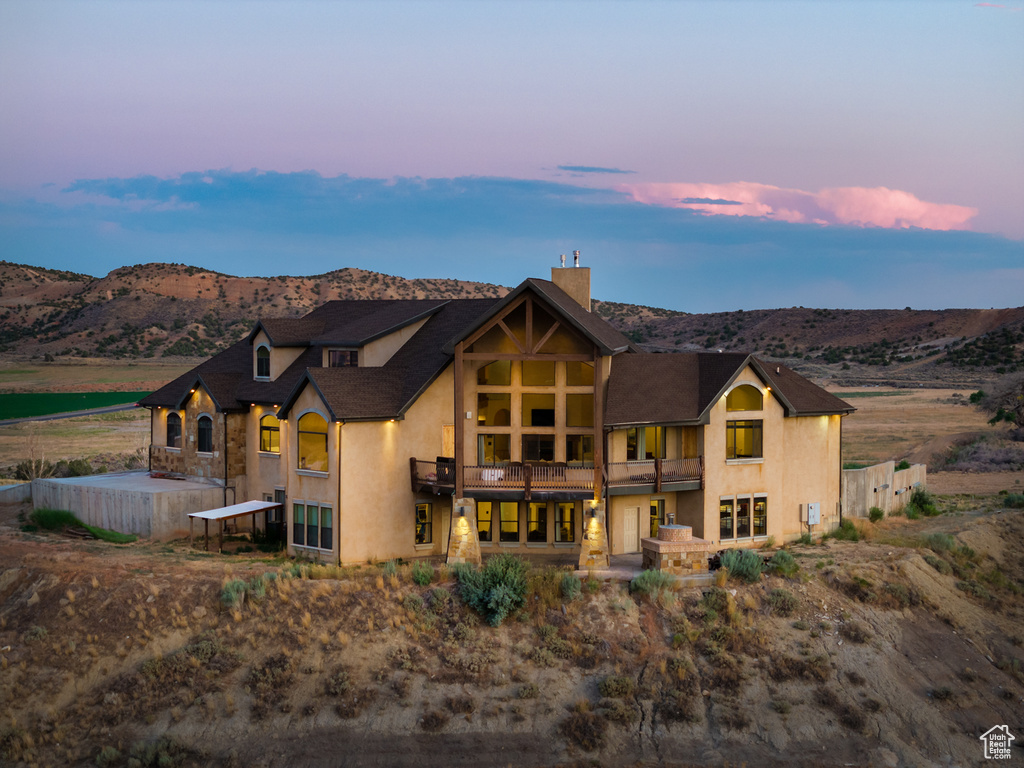 Back of house featuring a balcony, stucco siding, a mountain view, and a chimney