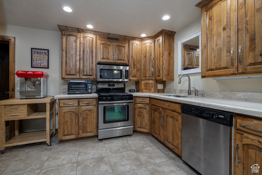 Kitchen with stainless steel appliances, brown cabinets, light countertops, and recessed lighting