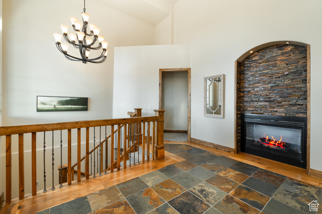 Corridor with stone tile flooring, an upstairs landing, a chandelier, and a high ceiling