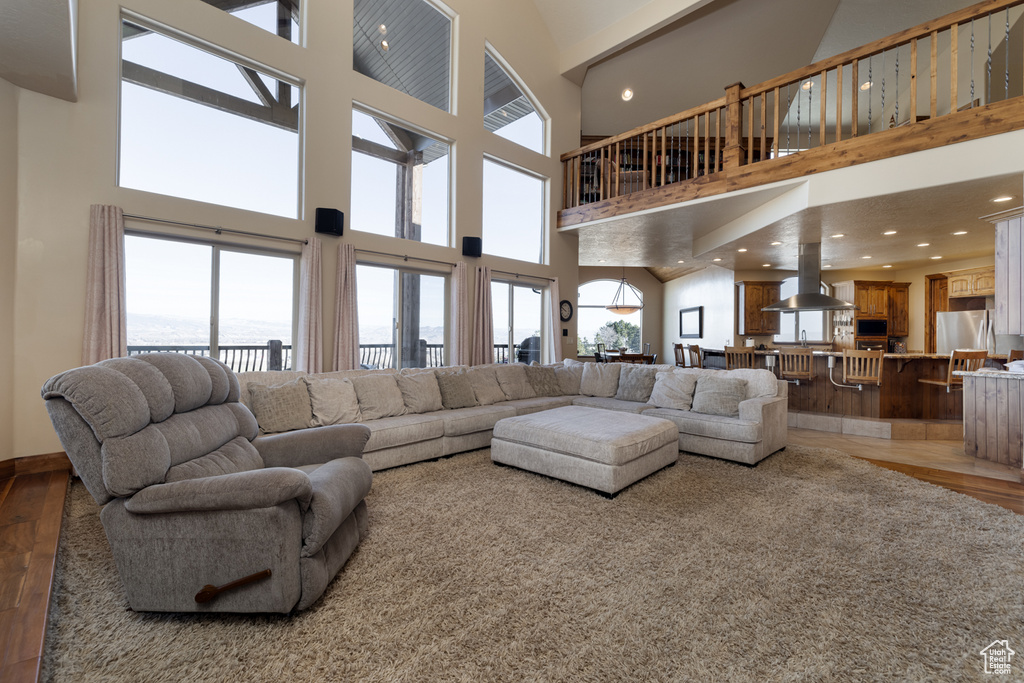 Living area with light wood-style flooring, a towering ceiling, and recessed lighting