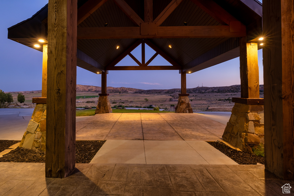 Patio terrace at dusk with a gazebo, a mountain view, and a patio area
