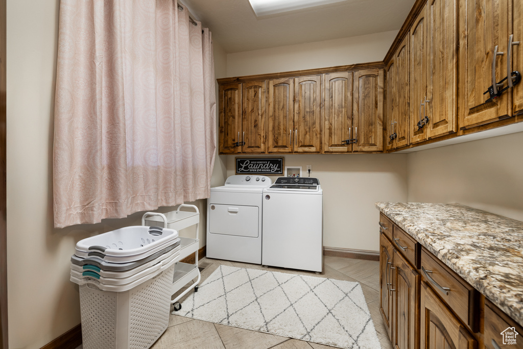 Laundry area with cabinet space, separate washer and dryer, and light tile patterned floors