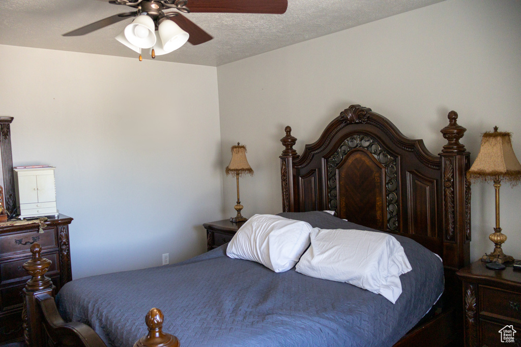 Bedroom with a textured ceiling and a ceiling fan
