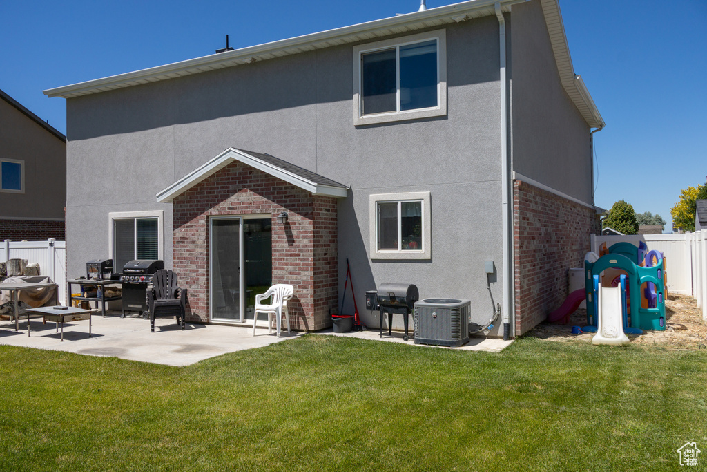 Back of house with brick siding, a patio area, a fenced backyard, and stucco siding