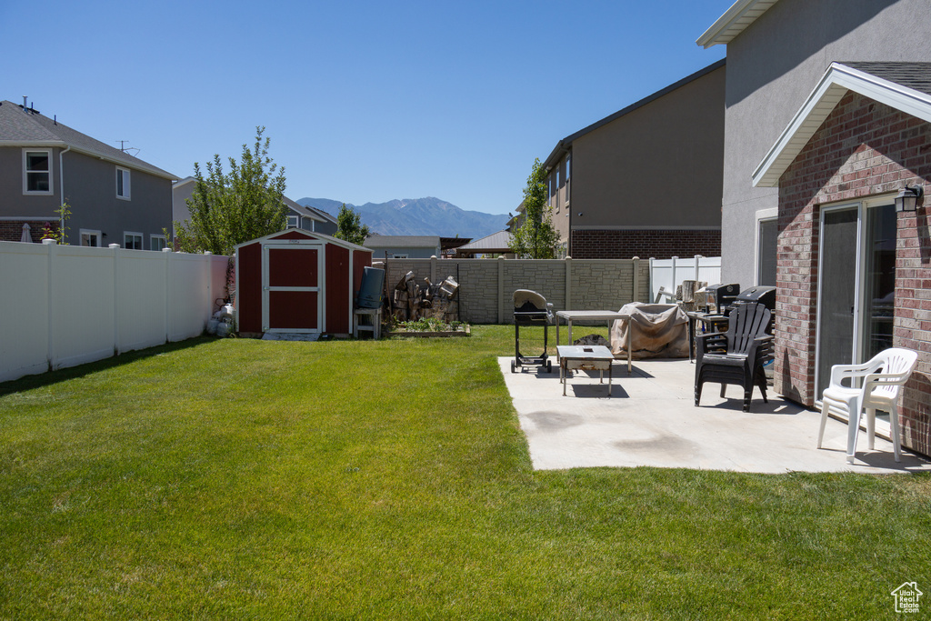 Fenced backyard with a shed, a patio area, and a mountain view