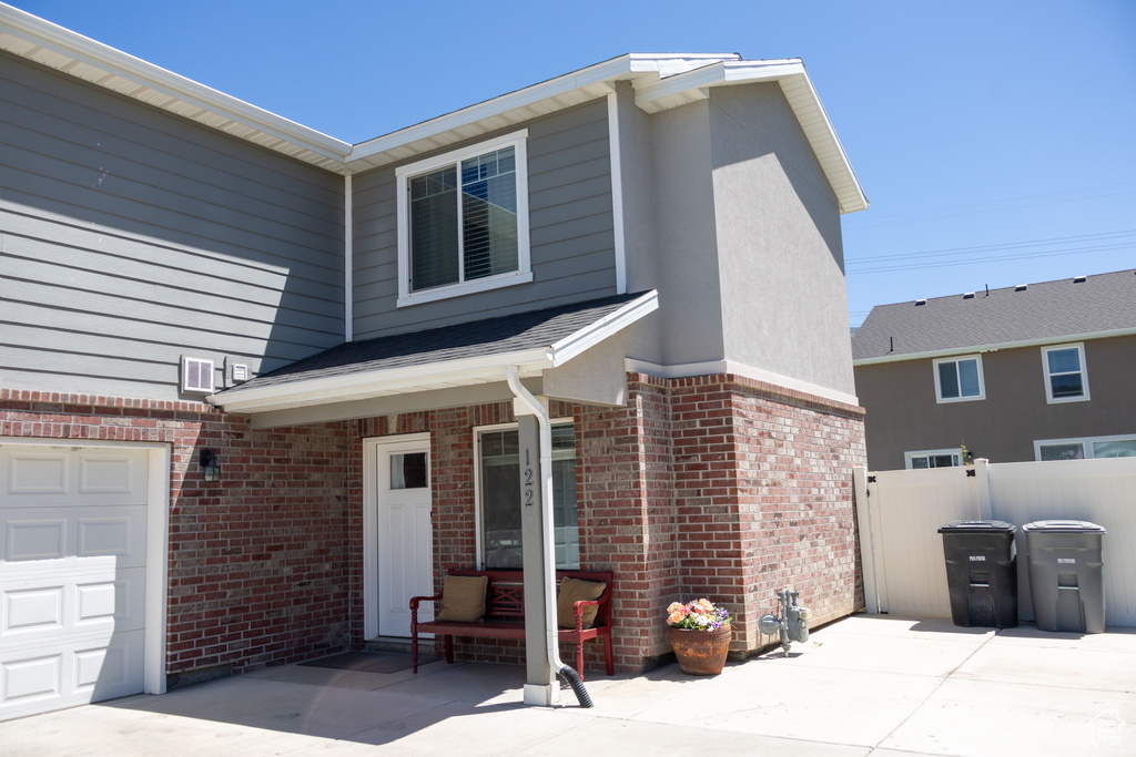 View of front of property with brick siding, a garage, and stucco siding