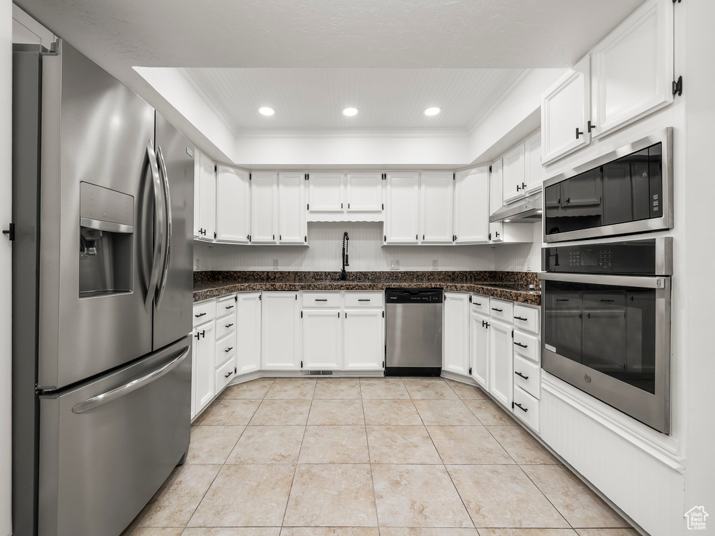 Kitchen featuring stainless steel appliances, a tray ceiling, light tile patterned floors, white cabinets, and recessed lighting