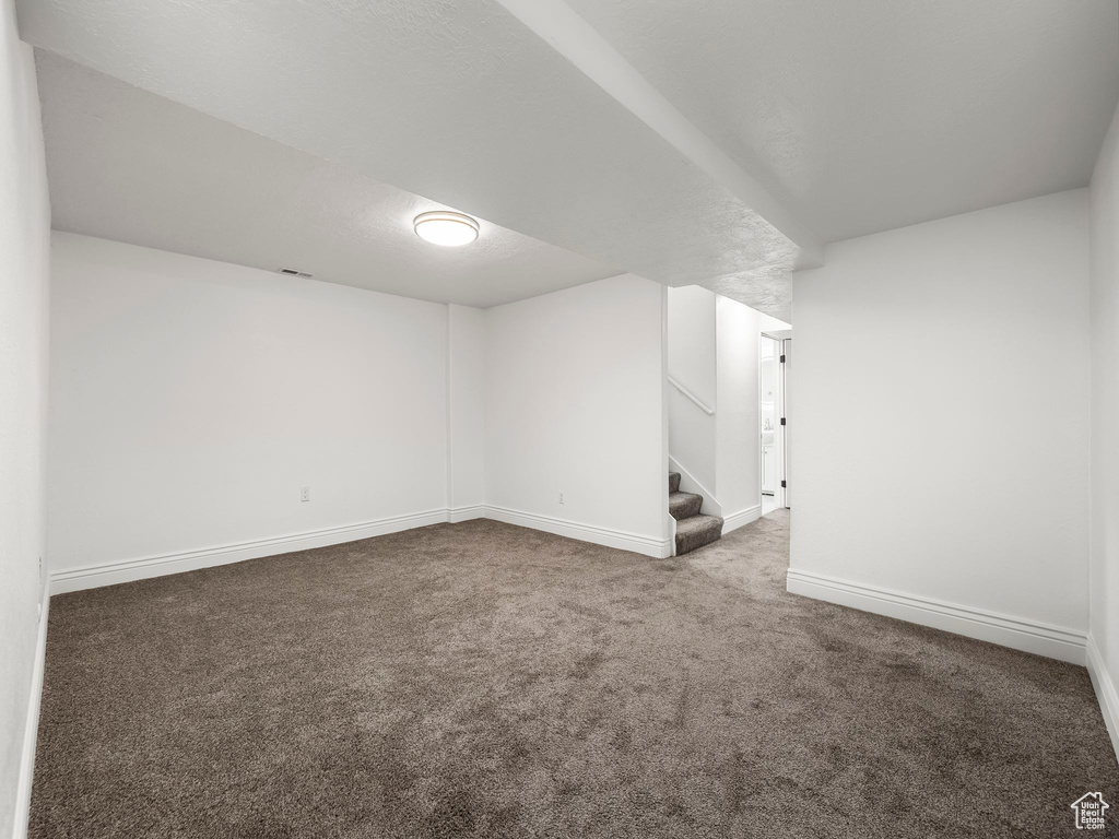 Carpeted empty room with stairs and baseboards