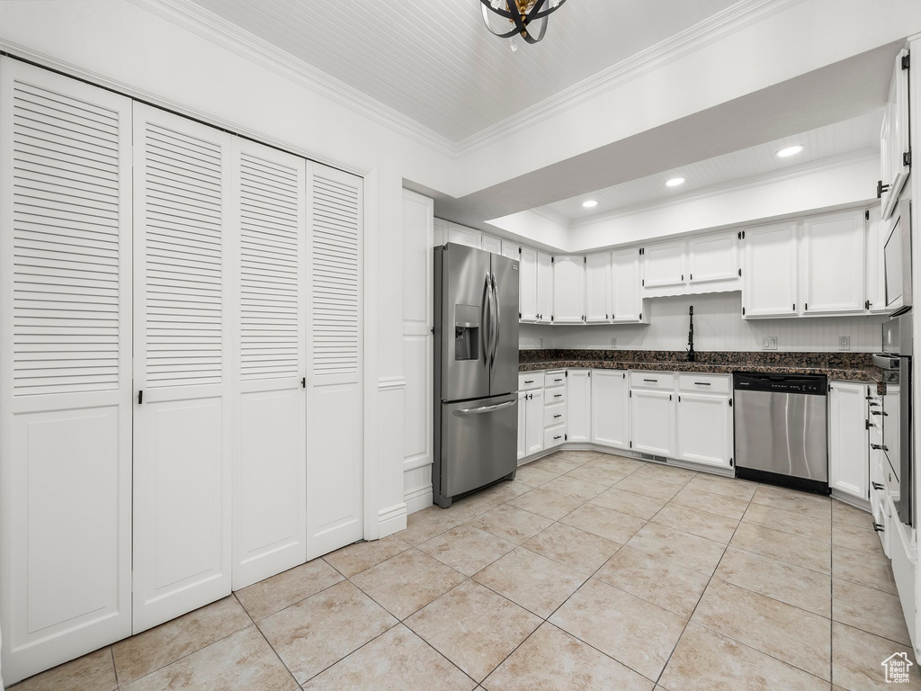 Kitchen with appliances with stainless steel finishes, crown molding, light tile patterned floors, white cabinetry, and recessed lighting
