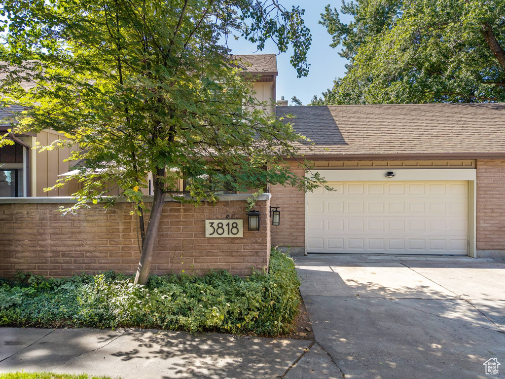 View of front facade with brick siding, concrete driveway, a shingled roof, board and batten siding, and a garage