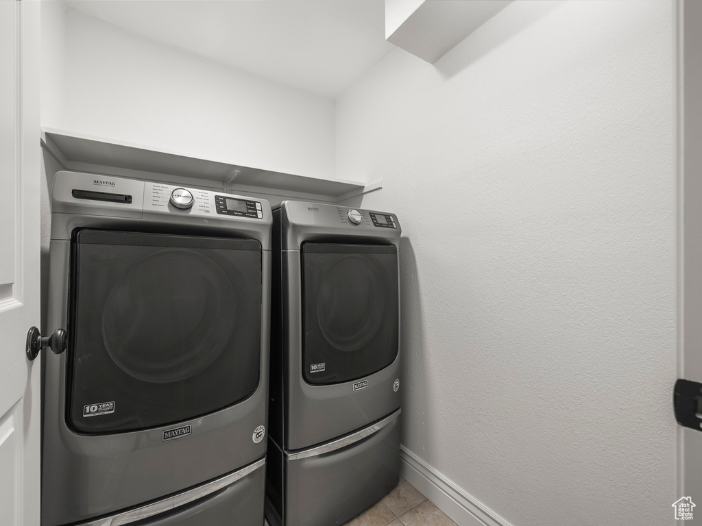 Laundry area with washing machine and clothes dryer and light tile patterned floors