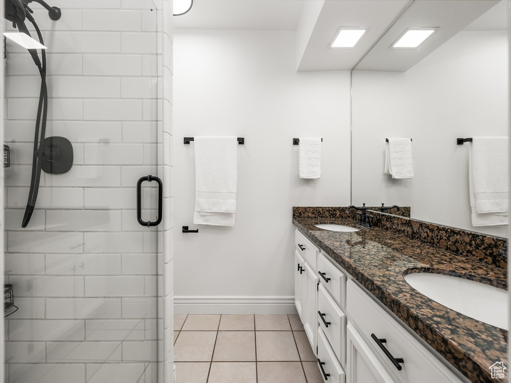 Bathroom with a stall shower, double vanity, and tile patterned flooring