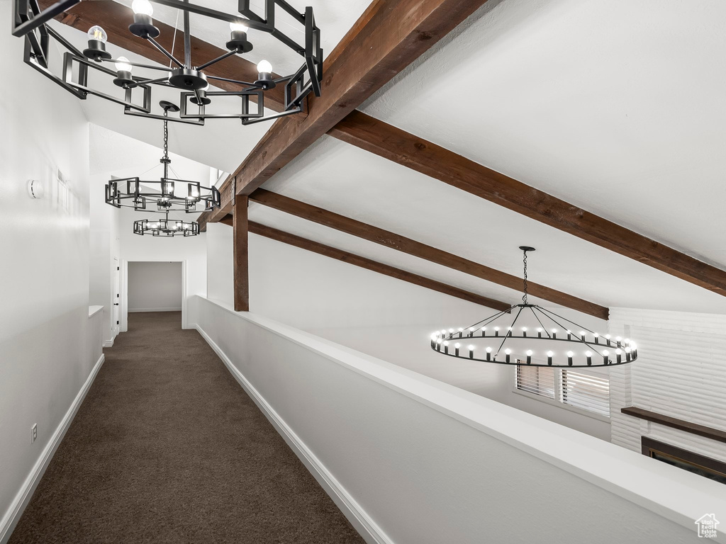Corridor featuring a chandelier, beam ceiling, and carpet