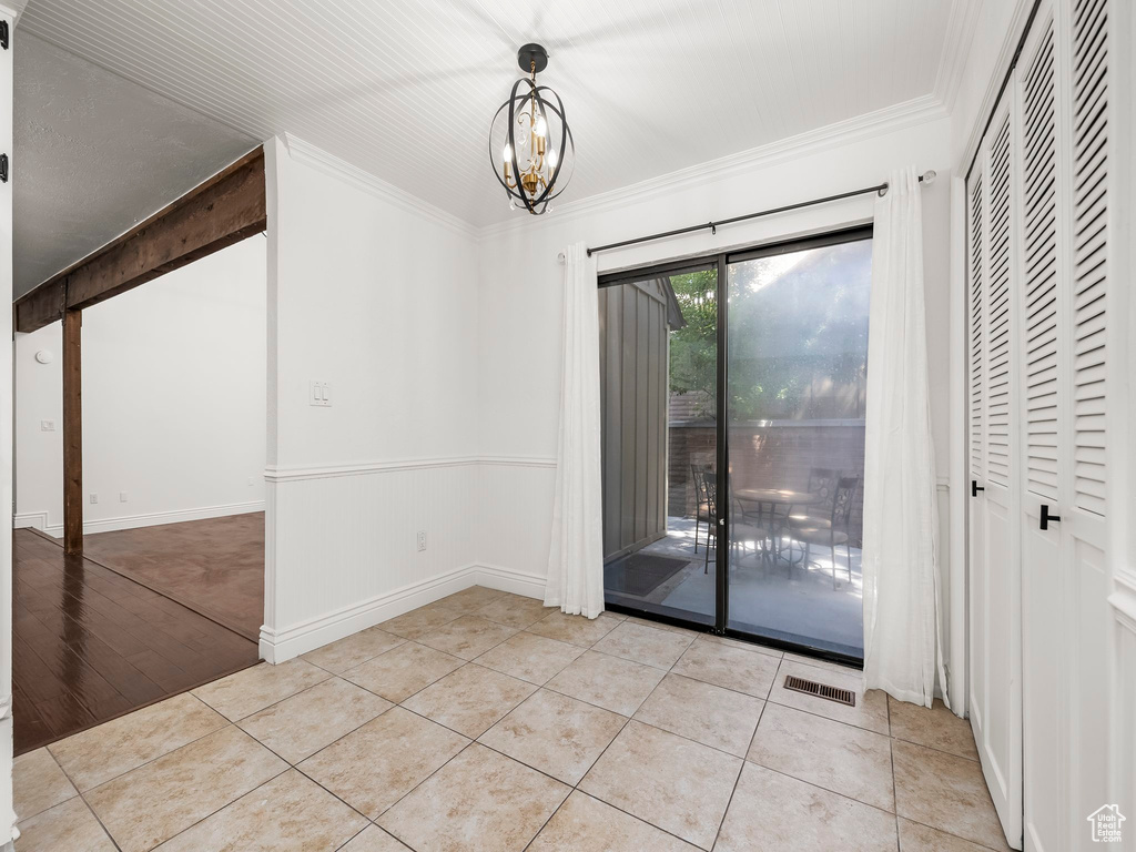 Unfurnished dining area featuring crown molding, a chandelier, and tile patterned flooring