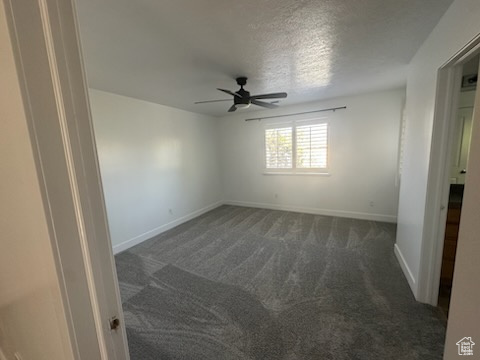 Carpeted empty room with a ceiling fan and a textured ceiling