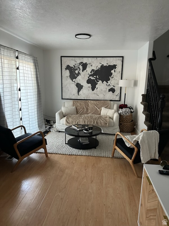 Living room with wood finished floors, a textured ceiling, and stairs