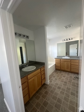 Full bathroom featuring two vanities and a garden tub