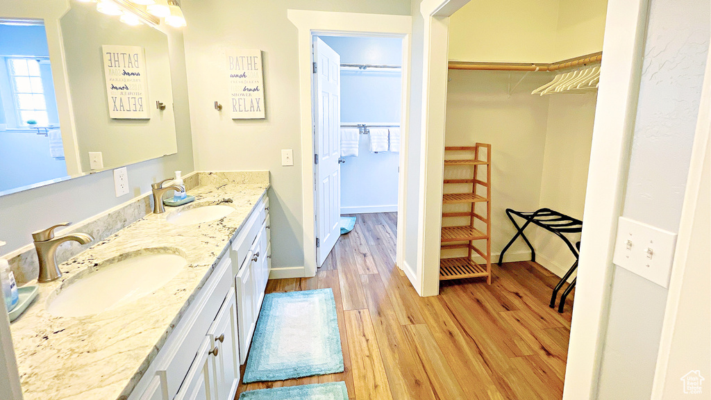 Bathroom with double vanity, wood finished floors, and a spacious closet