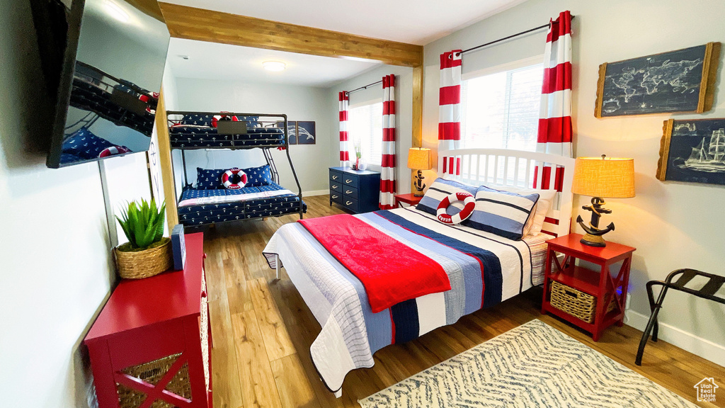 Bedroom with wood finished floors and beamed ceiling