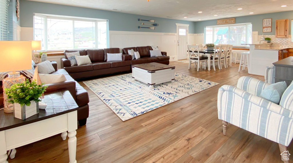 Living room with wood finished floors, wainscoting, and recessed lighting