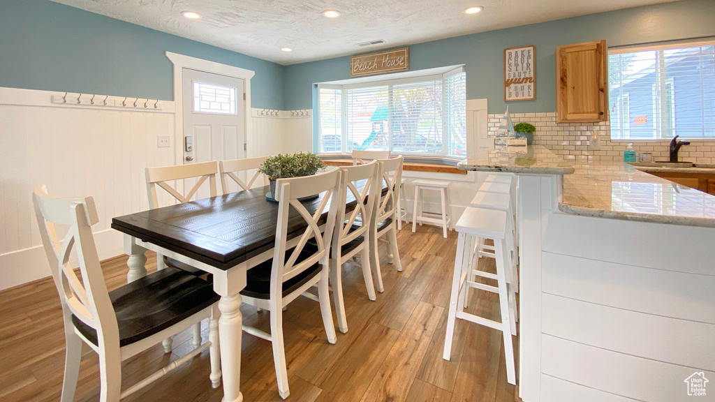 Dining area featuring recessed lighting, light wood finished floors, and wainscoting