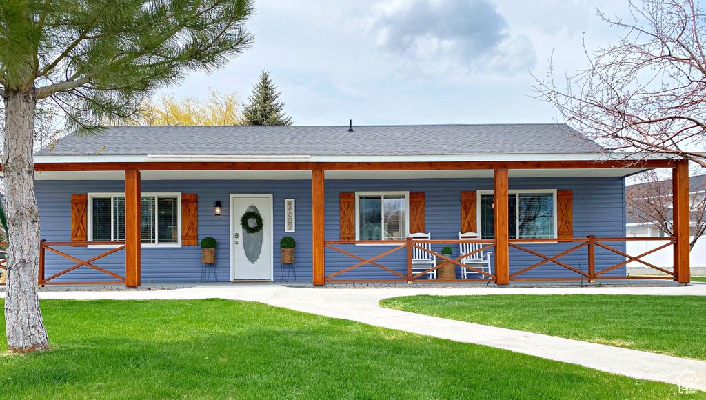 Bungalow featuring a porch, a front yard, and roof with shingles