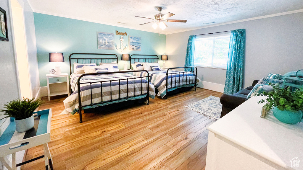 Bedroom with crown molding, light wood-type flooring, and a ceiling fan