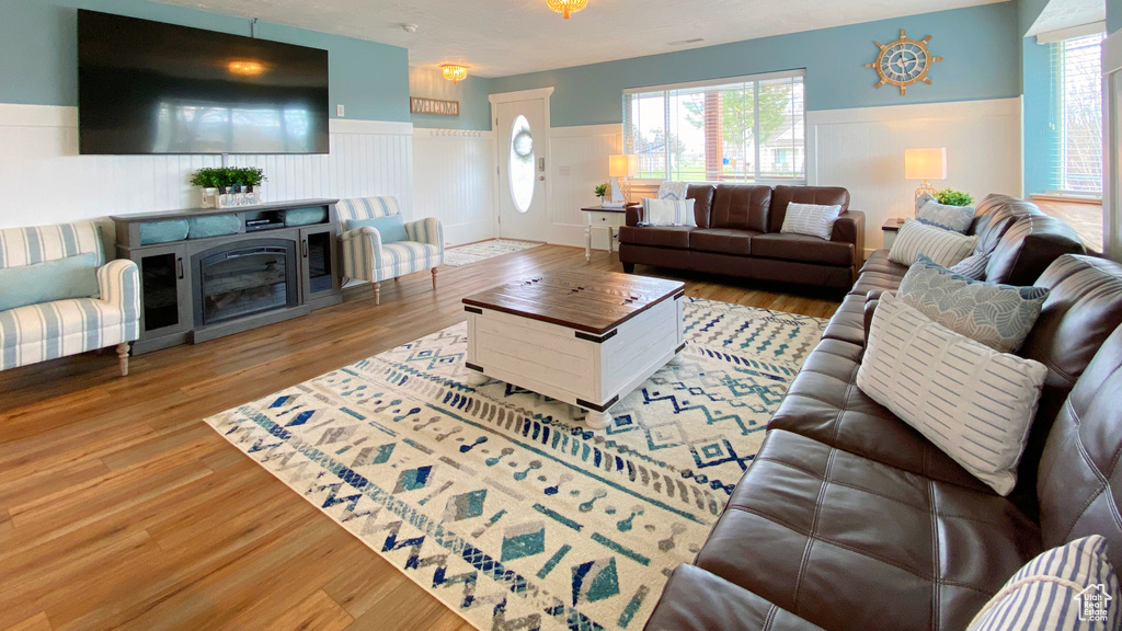 Living room with a wainscoted wall, wood finished floors, and plenty of natural light