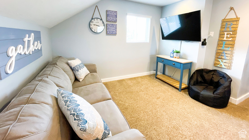 Carpeted living room with vaulted ceiling and baseboards