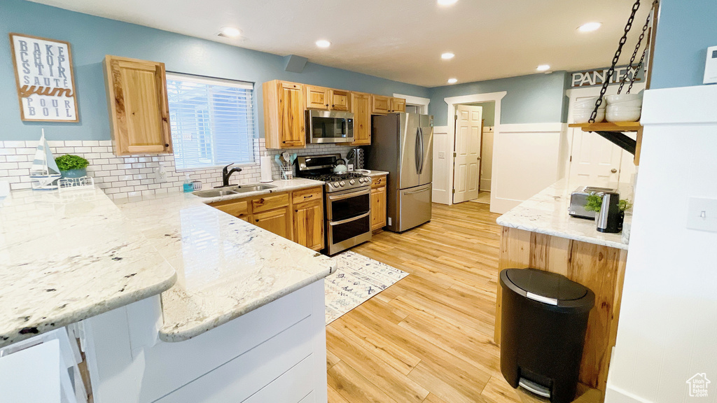 Kitchen with appliances with stainless steel finishes, tasteful backsplash, light wood-type flooring, recessed lighting, and light brown cabinetry
