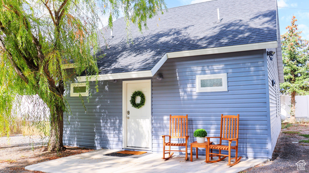 View of front facade with a shingled roof and a patio area