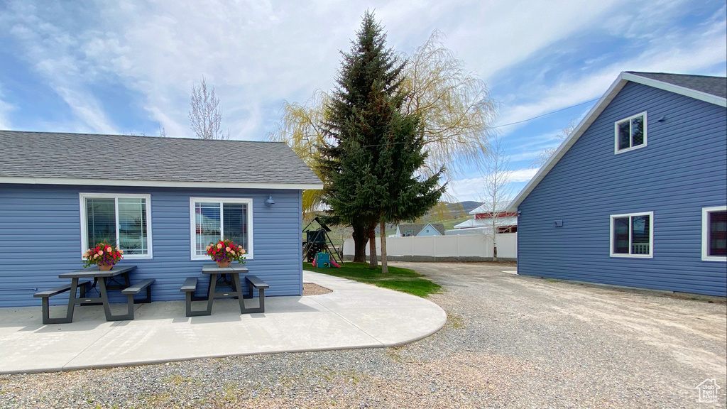 View of property exterior with a patio and roof with shingles