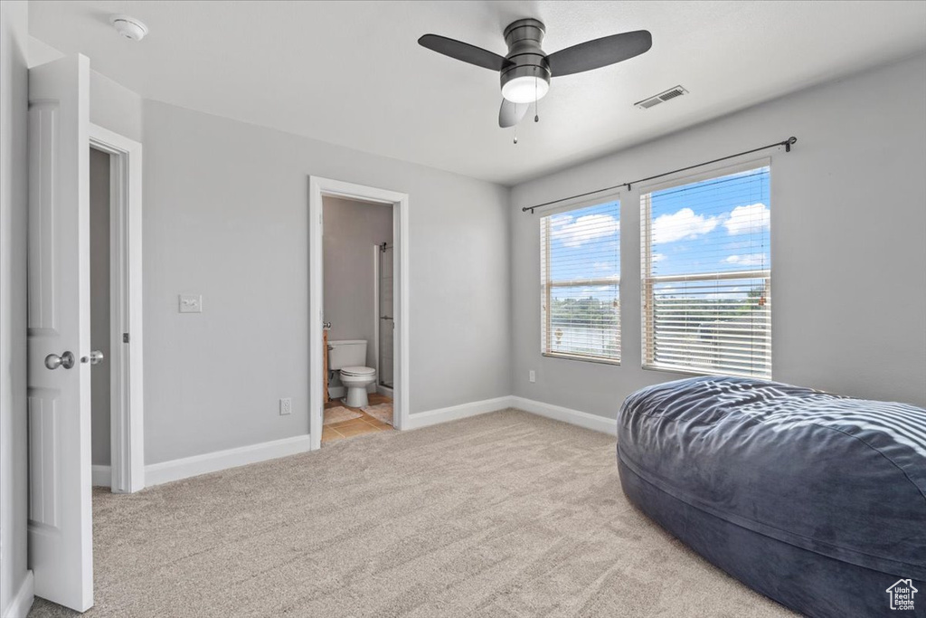 Bedroom with light colored carpet, connected bathroom, and ceiling fan
