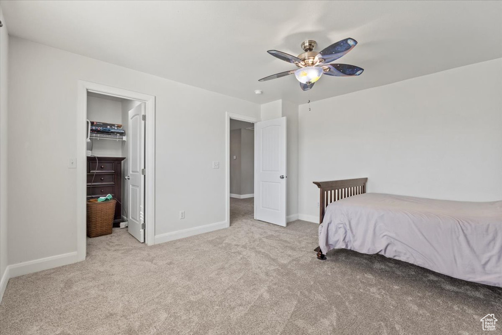 Carpeted bedroom featuring a ceiling fan and a walk in closet