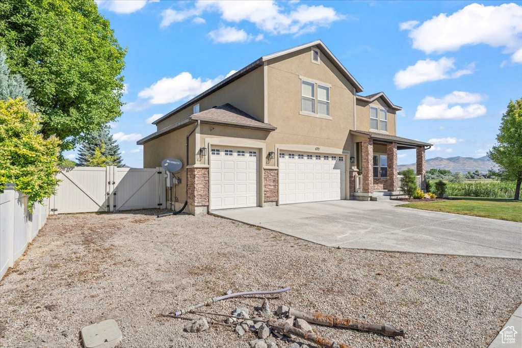 View of front of house with a gate, stucco siding, concrete driveway, a garage, and a mountain view