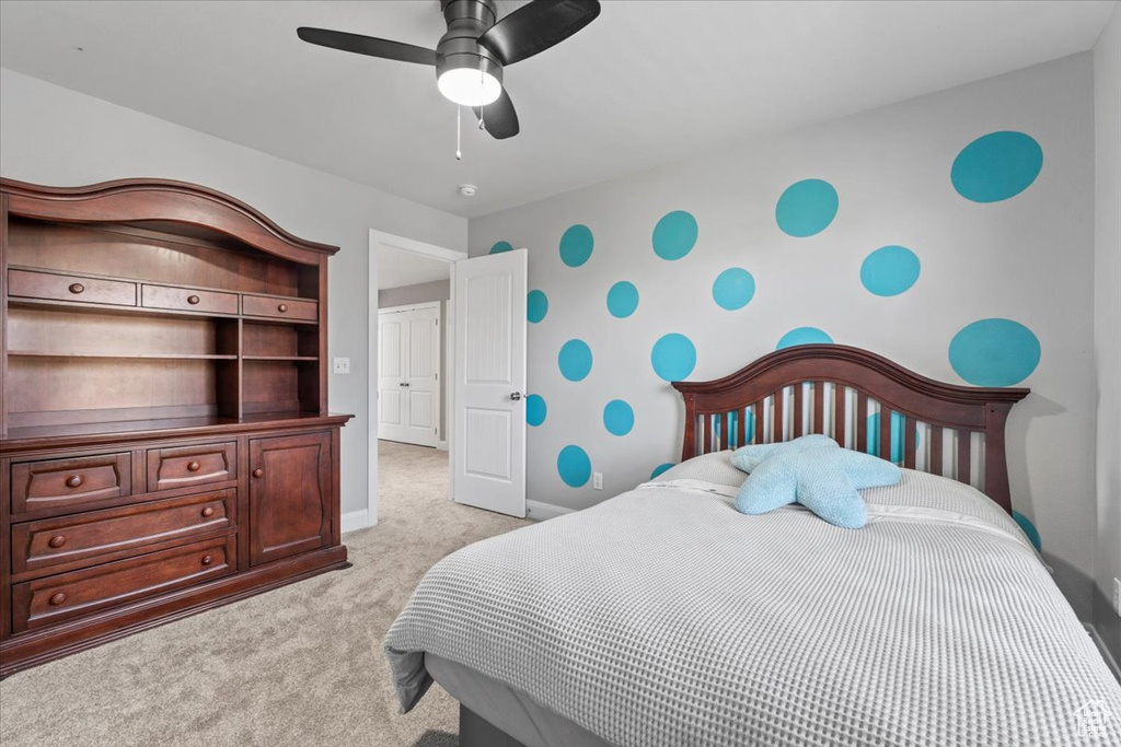 Bedroom with light colored carpet, wallpapered walls, and a ceiling fan