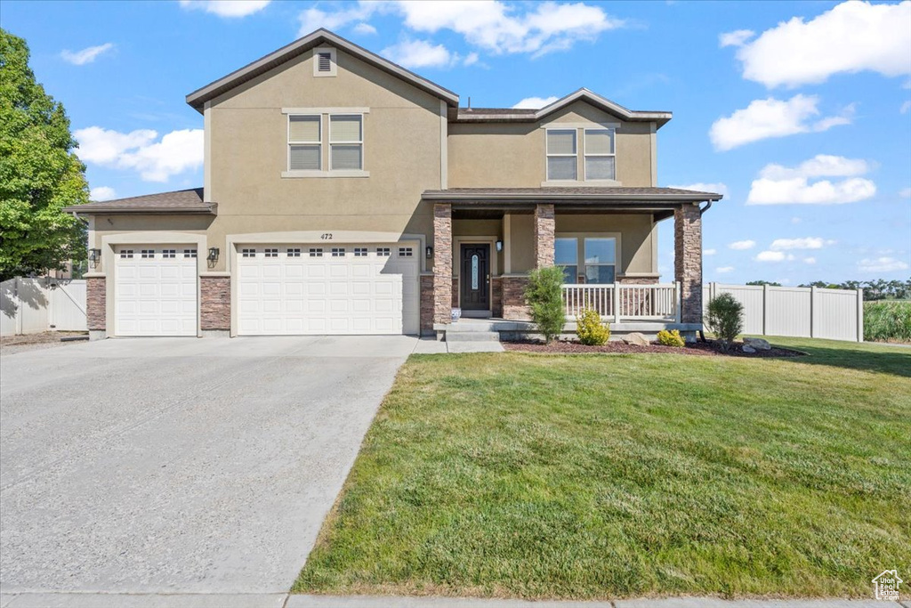 View of front of home featuring stucco siding, a porch, driveway, an attached garage, and stone siding