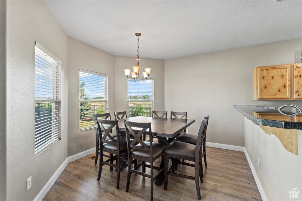 Dining room featuring healthy amount of natural light, light wood finished floors, and a chandelier