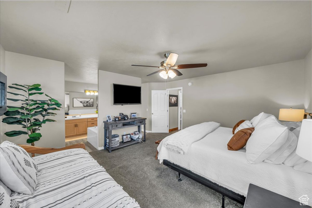 Bedroom featuring dark carpet, connected bathroom, and ceiling fan