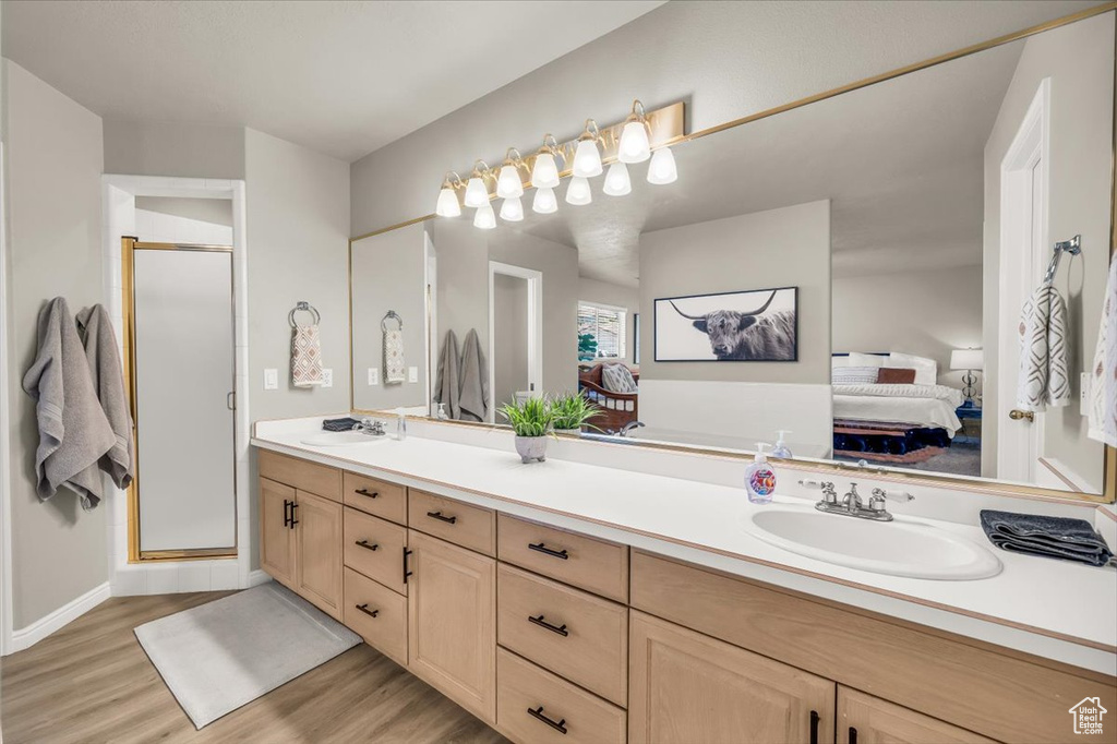 Ensuite bathroom with wood finished floors, double vanity, and a stall shower