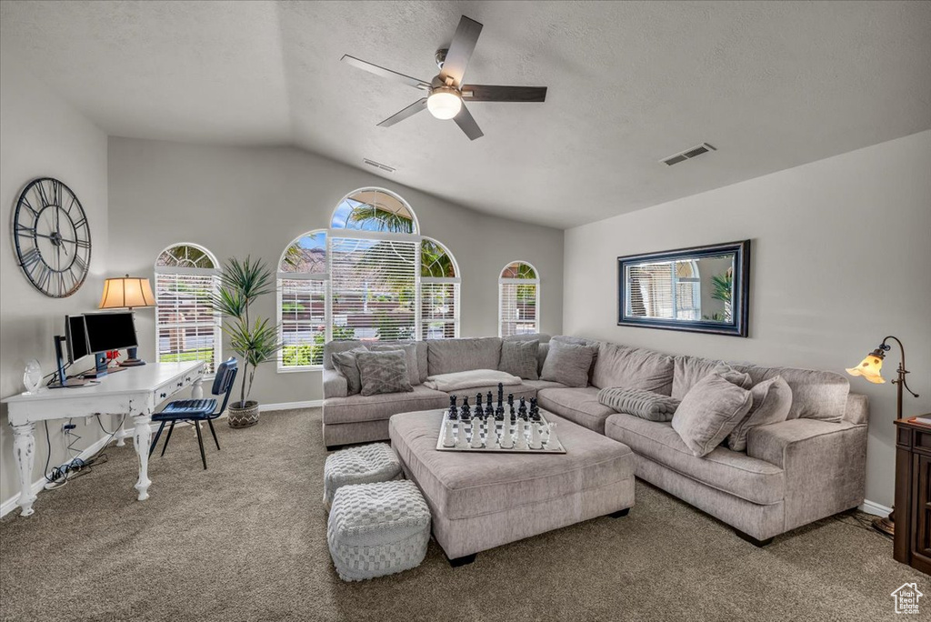 Living area featuring ceiling fan, carpet flooring, lofted ceiling, a desk, and a textured ceiling