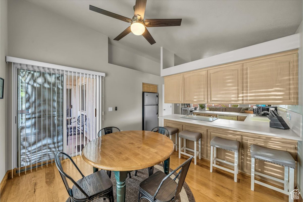 Dining room featuring ceiling fan, light wood-type flooring, and high vaulted ceiling