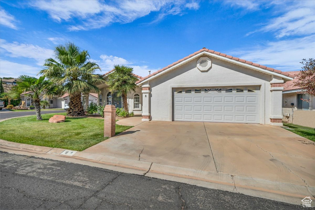 Mediterranean / spanish house featuring stucco siding, a tile roof, an attached garage, driveway, and a front lawn